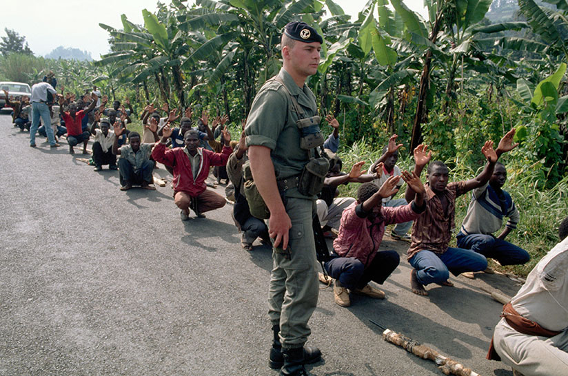 A French soldier walks past  a group of Interahamwe militia in training ahead of the 1994 Genocide against the Tutsi. / Net photo