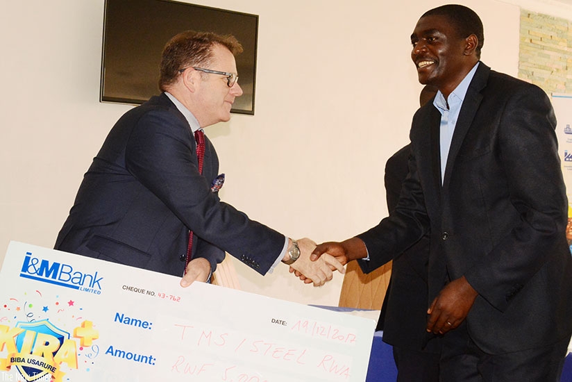 SteelRwa's Ndikubwimana (right) receives a dummy cheque of Rwf5m on behalf of the workers association, from Bairstow. / Frederic Byumvuhore.