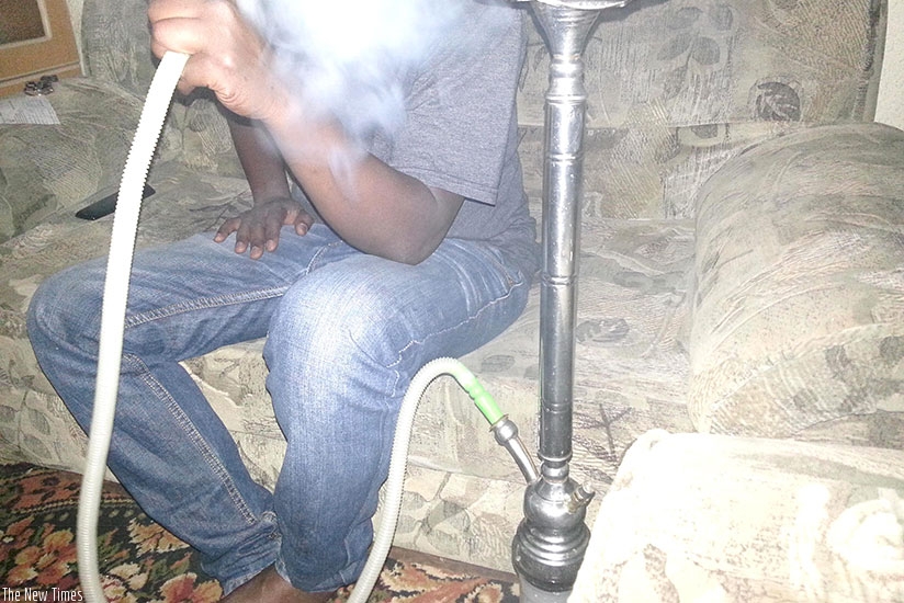 A person smokes shisha. Inset: A package of flavoured fruit used in shisha smoking. Courtesy.