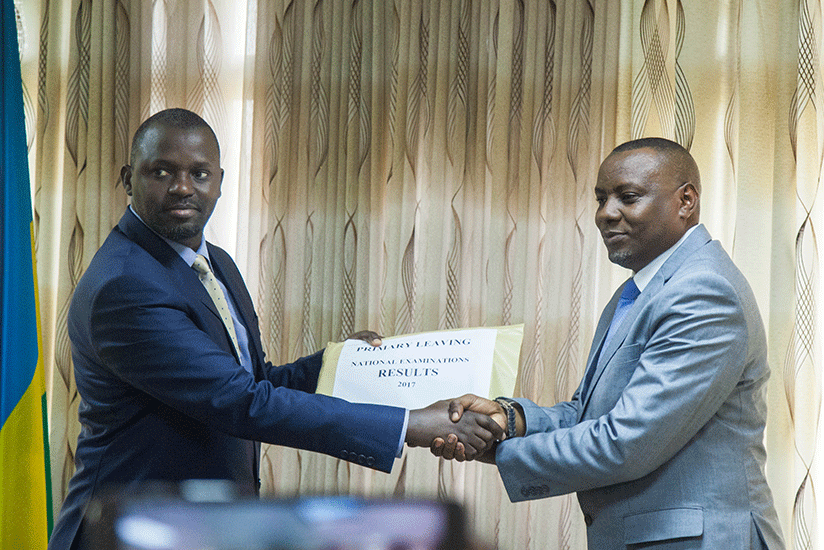 Gasana (left) hands over PLE results to Munyakazi yesterday. Nadege Imbabazi.