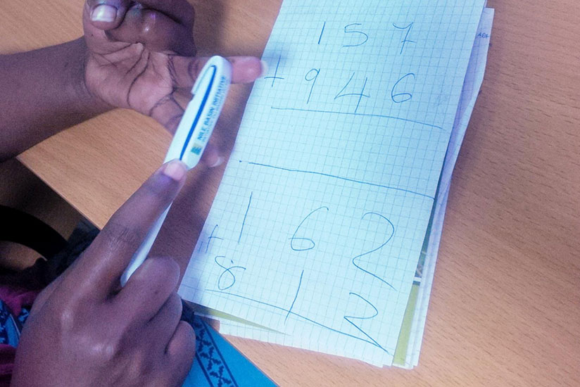 A pupil doing maths homework. (Joan Mbabazi)