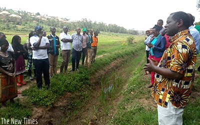 State minister for Agriculture, Fulgence Nsengiyumva (R) speaks to farmers and officials while assessing works at Rugende Marshaland last Friday. Emmanuel Ntirenganya.