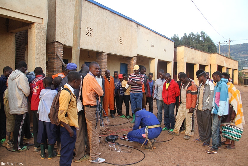 Residents in Ruhunde trading center watch as technicians install cash power meters / Photos: Mudingu Joseph