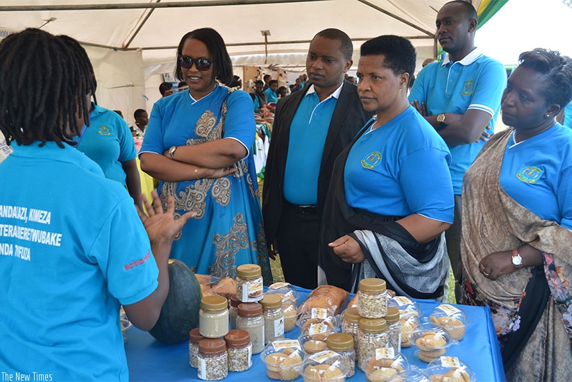 A female exhibitor explains to officials how she makes products from pumpkin seeds during national celebrations of the International Womenu2019s Day in Shyogwe Sector, Muhanga Di....