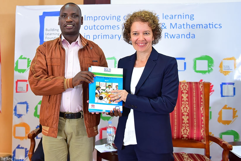 Amb. Lomas (right) gives a teachers' toolkit book to a teacher under the Building Learning Foundations programme. (Kelly Rwamapera)