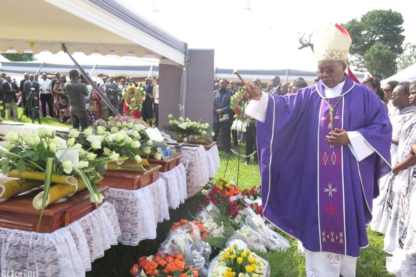 Bishop Philippe Rukamba of Butare Diocese sprinkles holy water on caskets containing the remains of some of the Genocide victims at the former ISAR Rubona in Huye District before t....