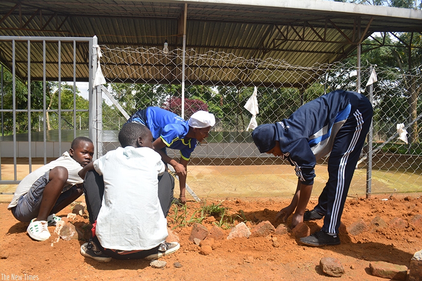The youth arrange bricks outside the memorial. F. Byumvuhore