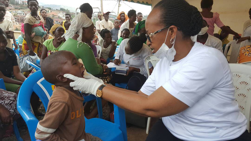 Adelaide Muhigana, a dental surgeon at Legacy Clinic checks a childu2019s teeth.  Marie Anne Dushimimana.