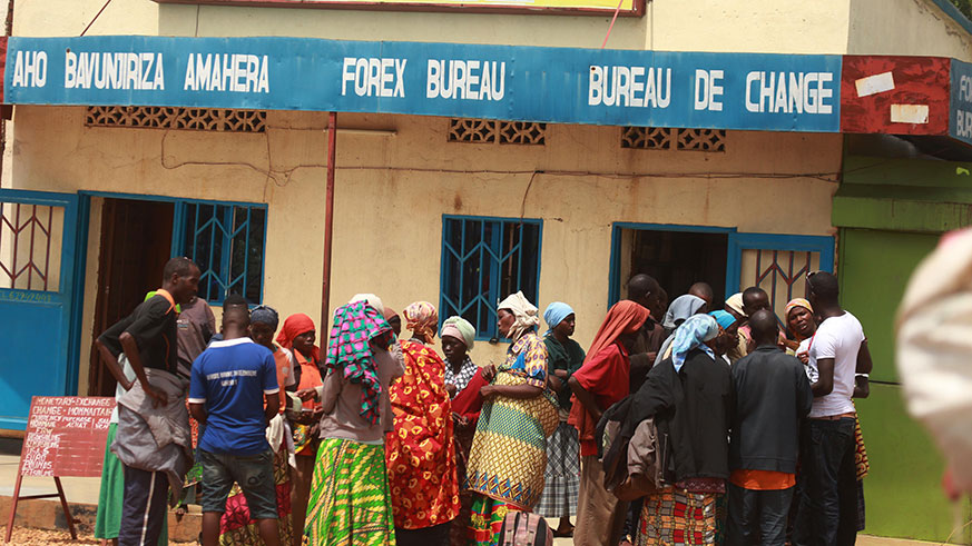 Asylum seekers exchange their money at the border after crossing to their home country