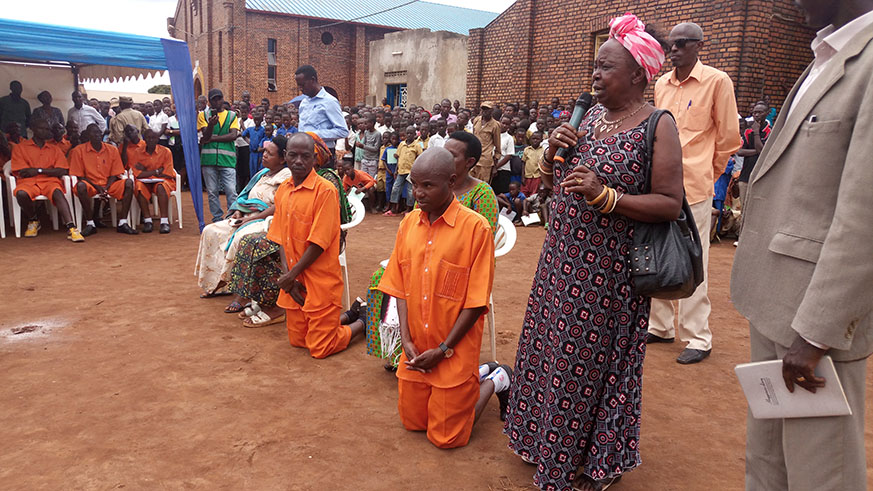 Rutayisire (L) and Rutaremara on their knees as their mother Twagiramariya asks residents of Kiziguro, especially families of Genocide victims, to pardon them.  All photos / Athan Tashobya.