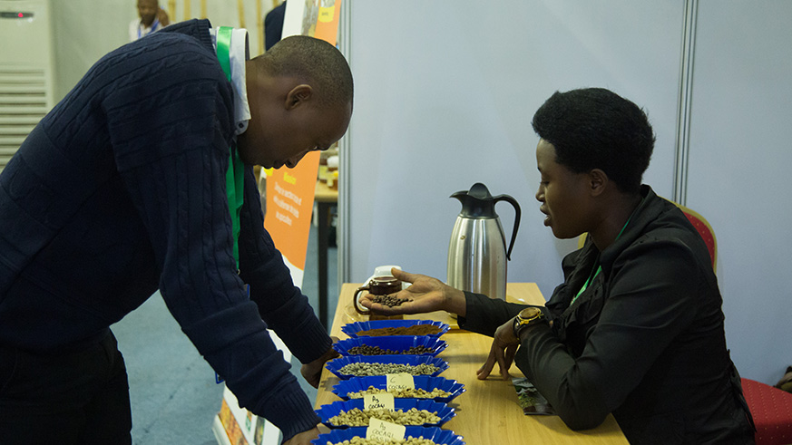 An exhibitor at the food production industry training showcases some of their coffee varieties to a showgoer.