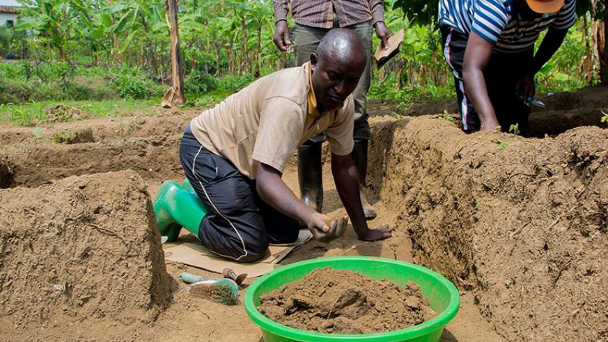 Ntagwabira and one of the two professional Rwandan archaeologists scrub soil from the former king's palace for sample analysis. (Faustin Niyigena)