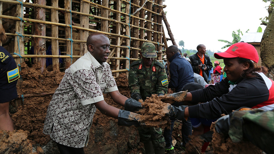 A resident serving the Minister Kaboneka with the mud to cover the house for a vulnerable citizen from Musanze Sector, Musanze District. Regis Umurengezi