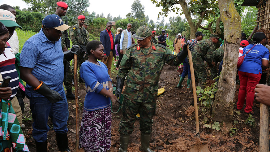 Gen Patrick Nyamvumba charting with one  of the beneficiaries of RDF Citizen Outreach Programme as Governor Gatabazi looks on