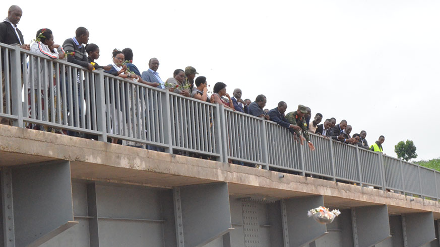 Officials and other mourners pay tribute to the victims of the Genocide against the Tutsi, including throwing flowers into the river on Sunday. Courtesy.