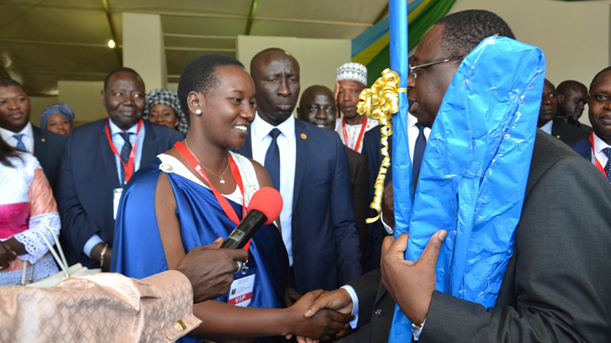 Minister Uwacu presents a gift to Senegalese President Macky Sall at the Rwandan stand at the ongoing festival in Dakar on Thursday. Courtesy.