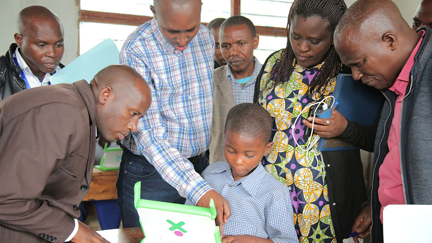 Robert Twongyeirwe, an inspector at the Ministry of Education (left); Emile Abayisenga, the Principal of IPRC-North (in checkered shirt); Thomas Kuradusenge, the head teacher at GS Nganzo I (centre, in checkered jacket); and Catherine Uwimana, the Vice Mayor for Social Affairs in Gakenke District look on as a pupil tries to operate a laptop provided under the OLPC programme. The officials were on Thursday visiting the school as part of the ongoing Quality Education Enhancement Awareness Campaign during which they have since established that some primary schools donâ€™t put OLPC computers to good use. Regis Umurengezi.