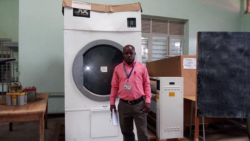 Jerome Habanabakize, the E.S.T.B manager standing in front of unused fridge that the school received from Skills Development Project (SDP). Regis Umurengezi
