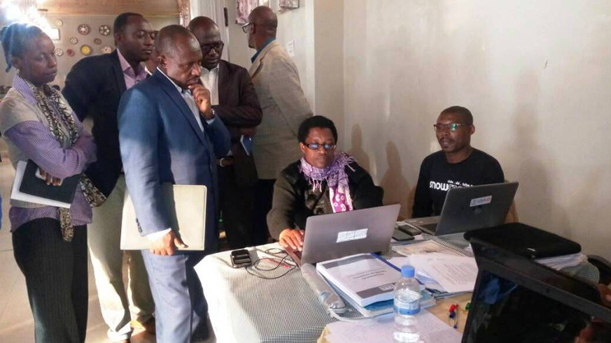 Education minister Mutimura (2nd left) checks the work done by one of the content writers. Regis Umurengezi.
