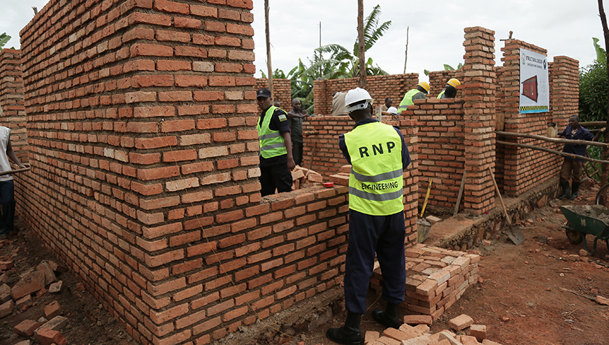 Police officers construct one of the village offices. NadÃ¨ge Imbabazi.