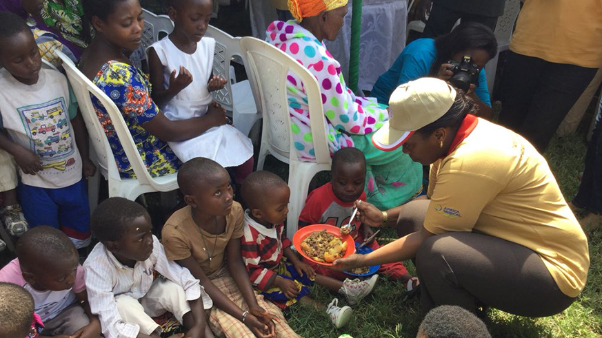 Minister Gashumba feeds children during the launch of the Integrated Maternal and Child Health Week in Rubavu District. (Diane Mushiyimana)