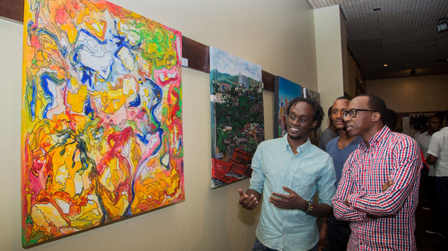Innocent Buregeya (left) explains his paintings to Atom, a local comedian, and other showgoers at an exhibition.  Right: Epa Binamungu working on an art piece. File photos