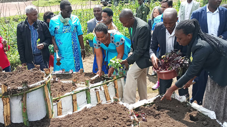 Officials planting vegetables in a garden kitchen of a resident from Bigogwe Sector, Nyabihu District.