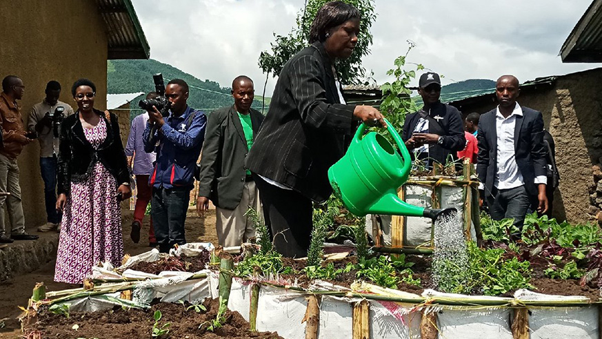 Minister of State for Local Government in charge of Social Affairs, Alvera Mukabaramba watering vegetables planted in Jeanette Uwamahoroâ€™s vegetable garden. (Regis Umurengezi)