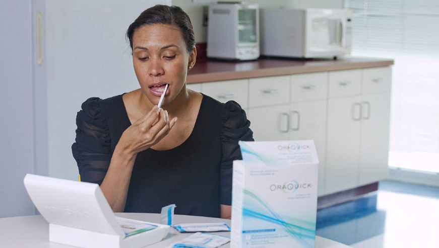 A woman demonstrates the OraQuick In-Home HIV Test, which detects the presence of HIV in saliva collected using a mouth swab. Net photo.
