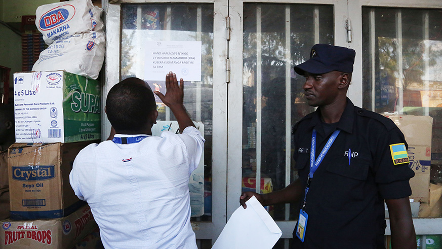 A Rwanda Revenue Authority's employee closes down a shop of one trader who is reported to  have defaulted taxes worth more than Rwf2 million in Kigali. Sam Ngendahimana.