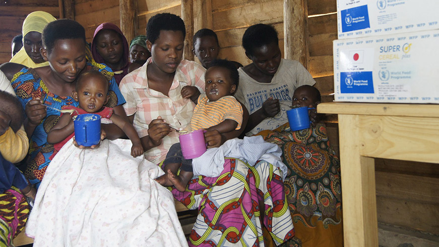 Refugee women server porridge to children in the the Burundian refugee camp of Mahama. Kelly Rwamapera