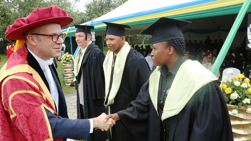 The Vice Chancellor of the University of Rwanda, Prof Phillip Cotton congratulating one of the officers who have been awarded master's degrees as other officers look on. Regis Umurengezi
