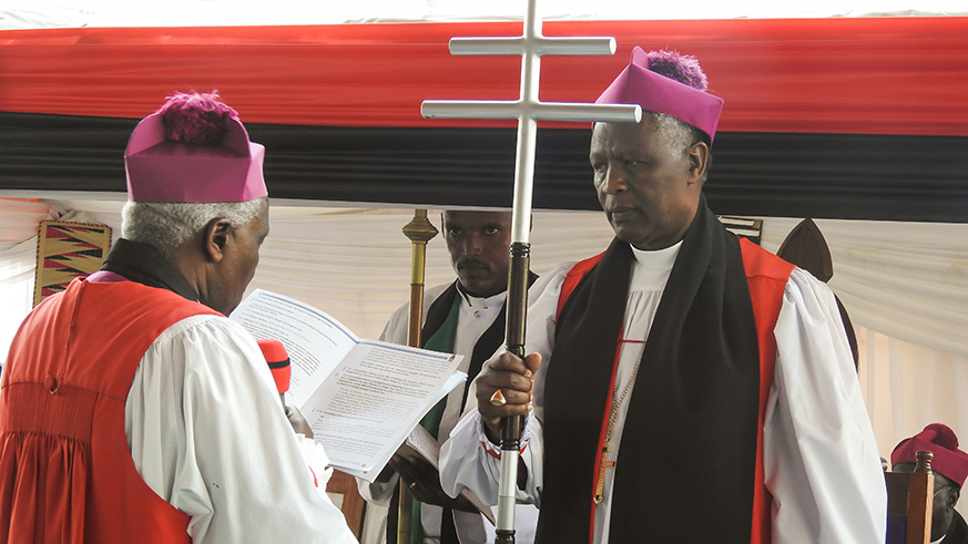 Former archbishop Onesphore Rwaje (left) hands over the crosier to the newly elected Archbishop of Anglican Church of Rwanda, Dr Laurent Mbanda, yesterday. / Frederic Byumvuhore