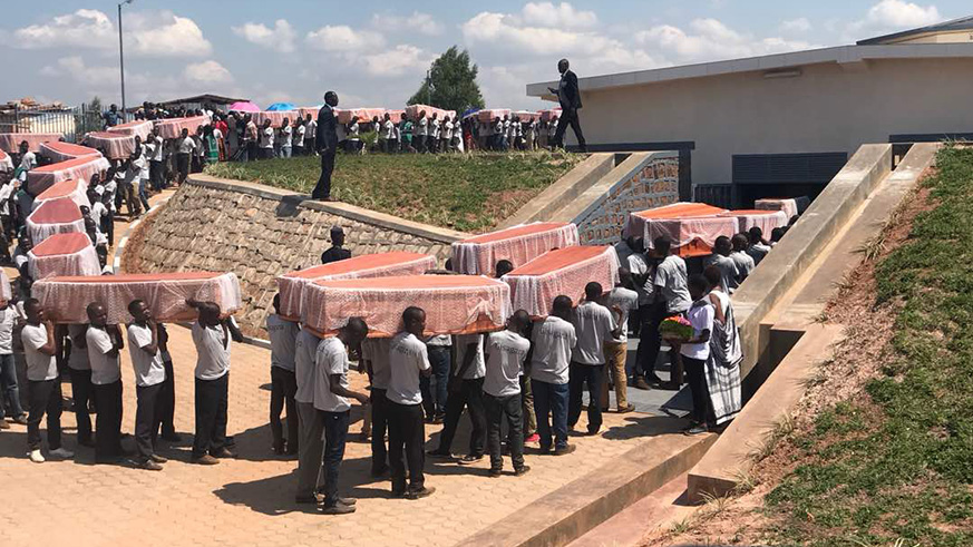 People carry the coffins of the victims who had been previously buried in different mass graves in Ndora sector to a new completed memorial. 