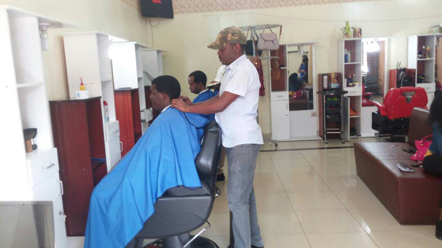A barber shaves of a clientu2019s hair at the saloon. All photos/Joan Mbabazi