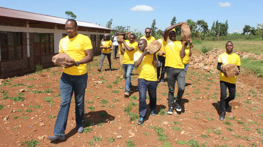 MTN staff carry stones to build foundation to put water tank.