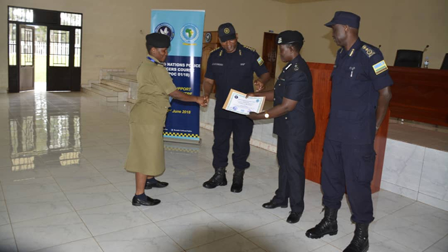 DIGP Juvu00e9nal Marizamunda (2nd left) awards a certificate to one of the course participants as the commandant of PTS CP Vianney Nshimiyimana looks on. Courtesy.