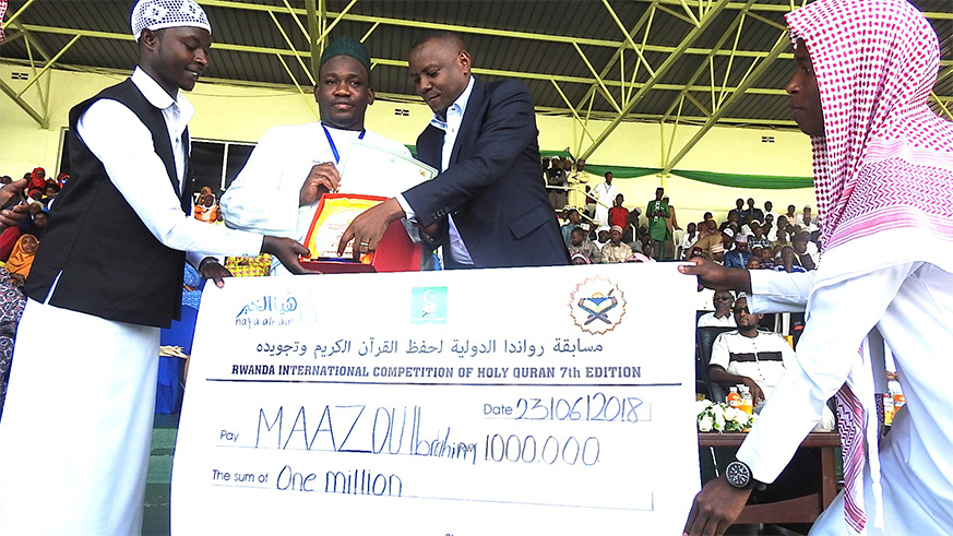 The Minister of State in charge of Primary and Secondary Education in the Ministry of Education, Isaac Munyakazi gives a medal and certificate to Nigerâ€™s Maazu Ibrahim Muadh, the overall winner.