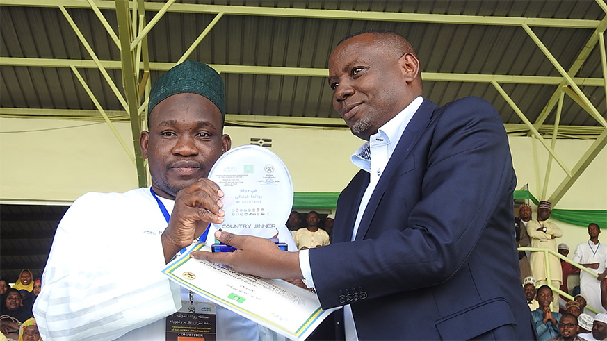 The Minister of State in charge of Primary and Secondary Education in the Ministry of Education, Isaac Munyakazi gives a medal and certificate to Nigerâ€™s Maazu Ibrahim Muadh, the overall winner.