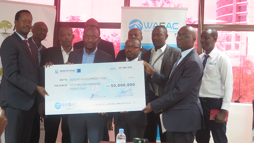 WASAC staff hand over a cheque of Rwf 50 million to Agaciro CEO Jack Kayonga (L)-Eddie Nsabimana