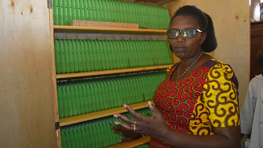 Jackqueline Mukangago the head mistress of E.P Kabuye showing the laptops that they now charge from school after they got connected to the national grid.