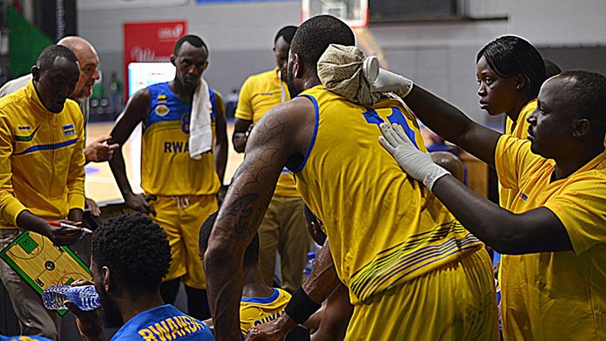 Players listen to coach Maxime Mwiseneza's instructions in a time-out during the third quarter of the game against Uganda on Sunday. Courtesy