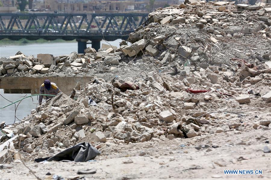 Workers search for bodies buried under debris at a spot in the old city of Mosul, northern Iraq, on July 5, 2018. More than 5,200 bodies have been retrieved during the past months, buried under debris of the devastated buildings in the old city center of the western side of Mosul, local official and civil defense police said on Thursday. (Xinhua/Khalil Dawood)