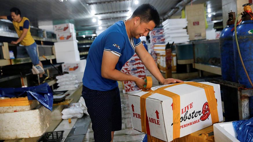 A customer closes a box of lobsters that are imported from the U.S. at a seafood retailer at a fish market in Beijing, China, June 27, 2018. Courtesy Reuters.