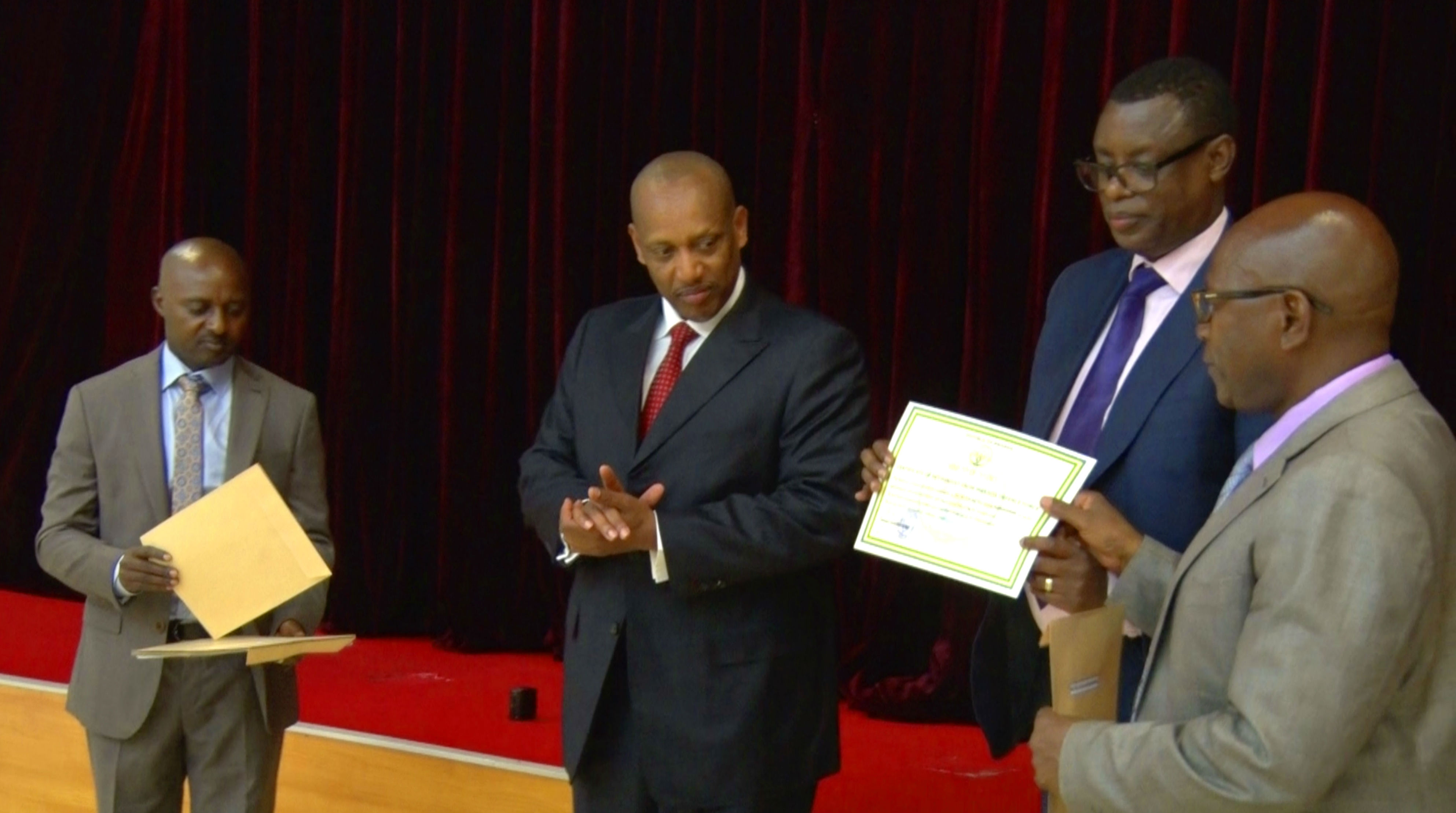 Maj Gen Jerome Ngendahimana (retired), the former RDF Reserve Force Deputy Chief of Staff (R) receives a certificate of retirement from Minister for Defence, Gen. James Kabarebe. Looking on in black suit is Gen. Patrick Nyamvumba, RDF's Chief of Defence Staff while on his right is Lt. Col. Peterson Mutsinzi, RDF's Acting chief of Administration and Personnel.  