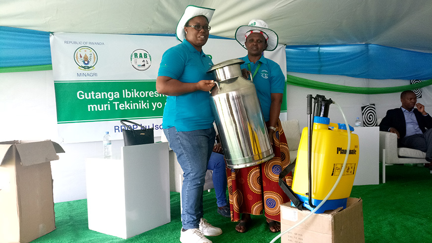 Dusabe (R) receives dairy farming equipment from RABu2019s Dr Uwituze as award for her cow u2018Mbabaziu2019 which won milk competition at Mulindi agriculture show ground in Gasabo District on Monday. Emmanuel Ntirenganya. 