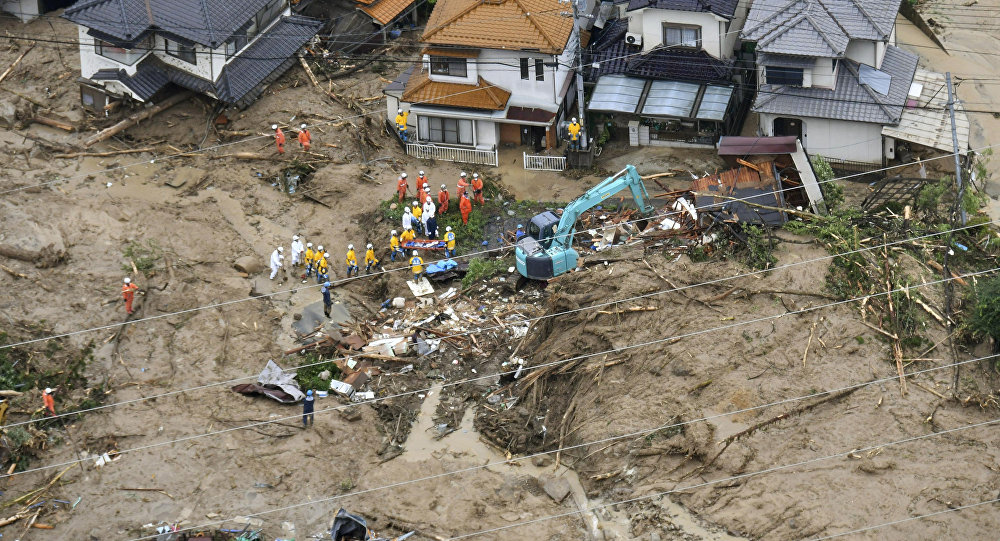 Rescue workers are seen next to houses damaged by a landslide following heavy rain in Hiroshima, western Japan, in this photo taken by Kyodo. / Sputnik