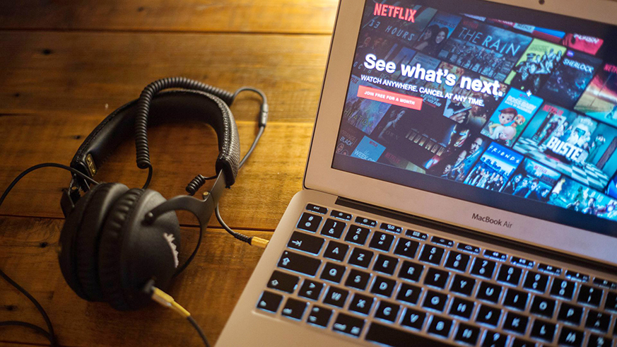 A pair of headphones next to a laptop, with the Netflix homepage pulled up. Net photo.