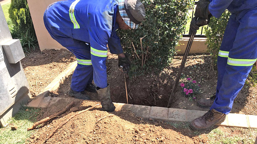 Workers transport a roll of conduit ducts for fibre optic cable. Net.