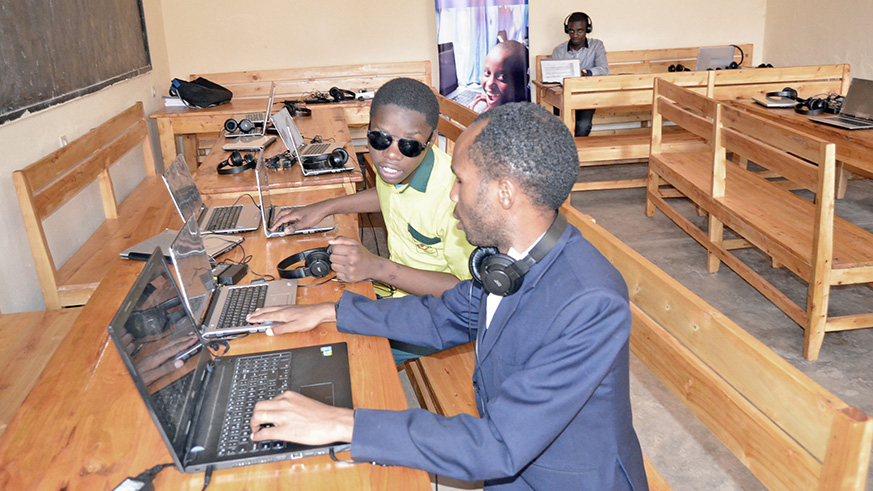 Innocent Vuguziga guides a visually impaired student during a computer lesson at Gatagara  Secondary School in Rwamagana. Photos by  Kelly Rwamapera